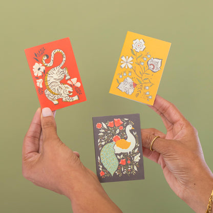 Hand-illustrated mini cards by Amita Nair held in hand