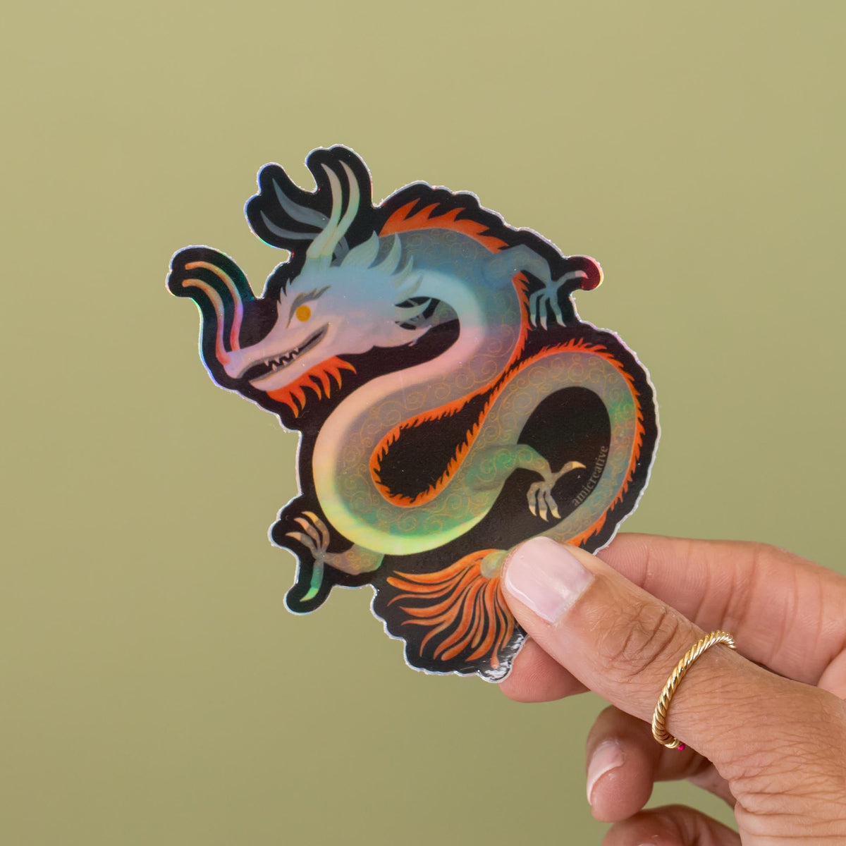 Dragon holographic vinyl sticker held in hand, blue and red dragon with holographic shine by Amita Nair